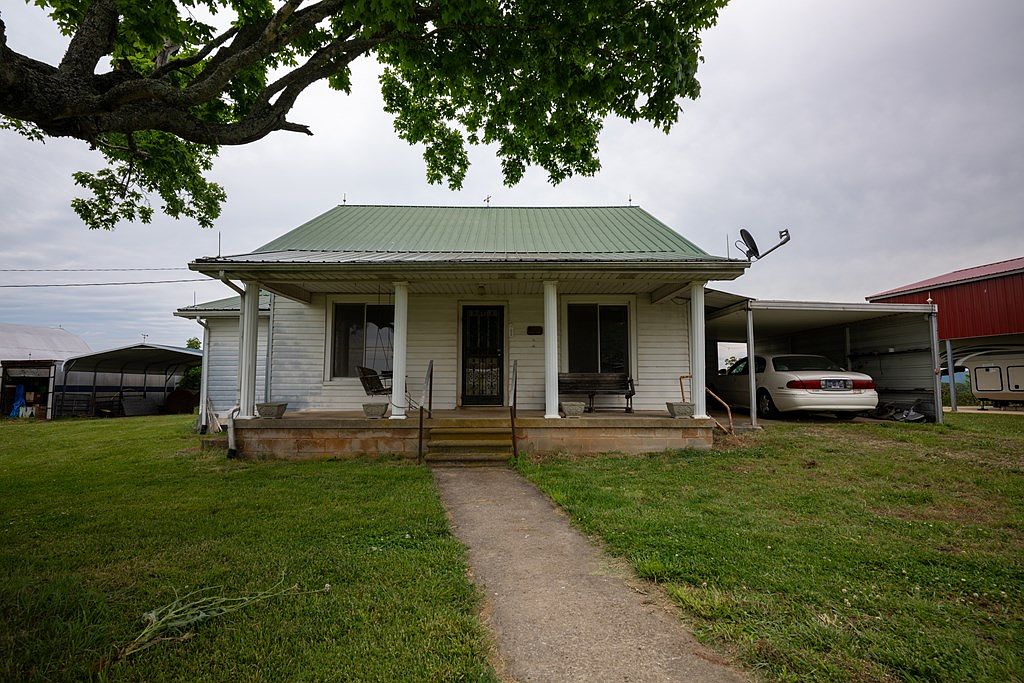 Front elevation of the 1955 white clapboard farmhouse showing the porch with columns, the front steps, and the front walk in cut grass