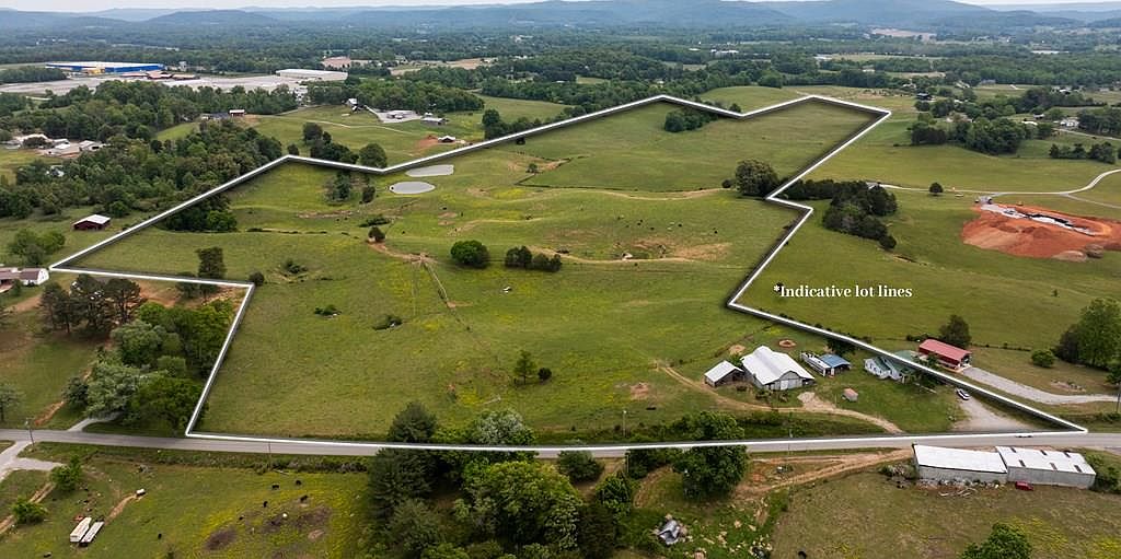 Aerial of 1496 S Bunker Hill Road showing the indicative lot lines around 83 acres of pasture, hay fields, and farm structures with the Upper Cumberland ridges in the distance